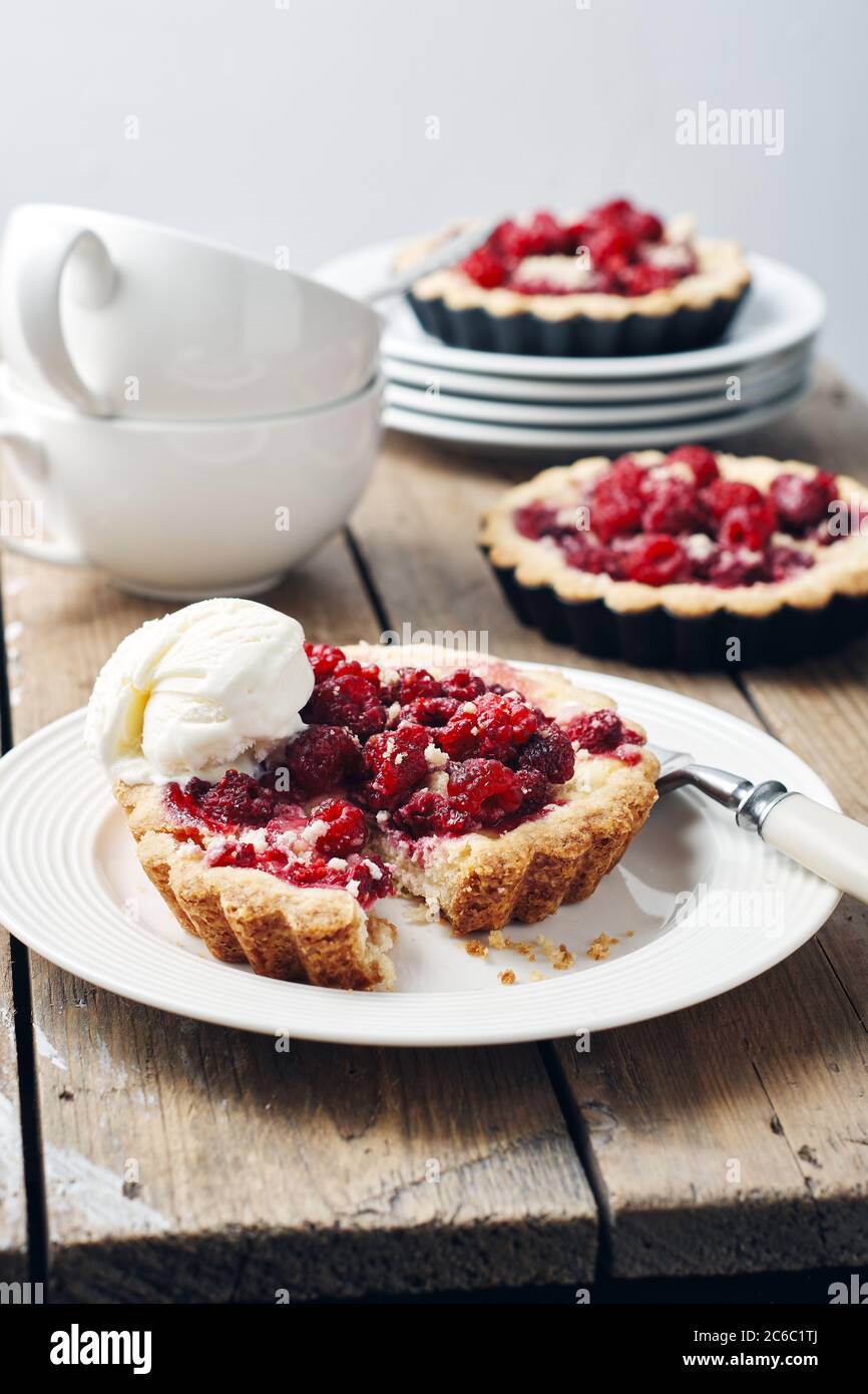 Mini-chaussons cuits aux framboises sur une table rustique en bois. Banque D'Images