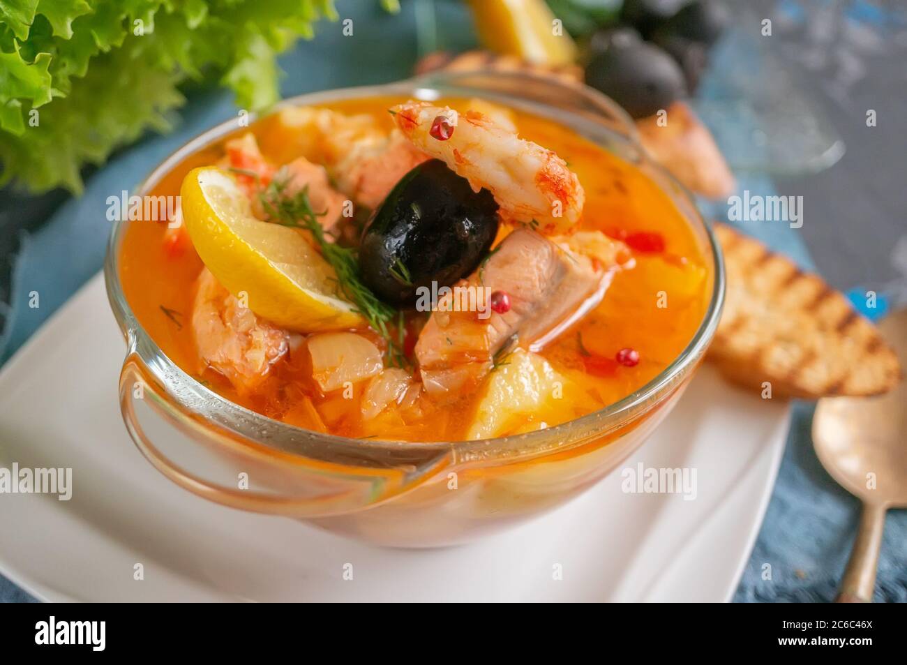 Les fruits de mer, saumon et soupe à la morue avec des pommes de terre. Servi avec du citron, les olives et délicieux croûtons de pain blanc. Close up. Banque D'Images