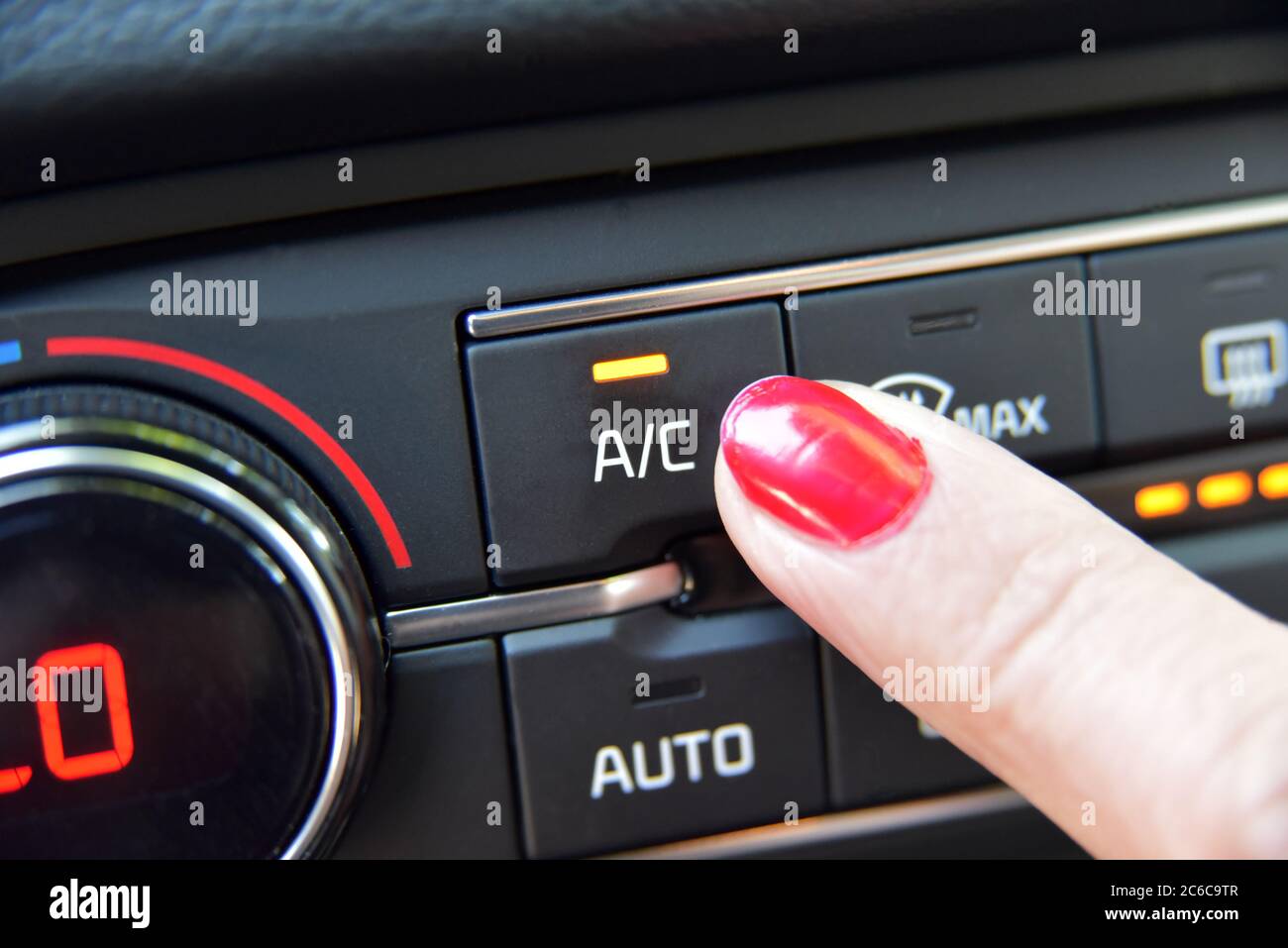 Gros plan de la main d'une femme en appuyant sur le bouton de mise en marche de la climatisation une voiture Banque D'Images