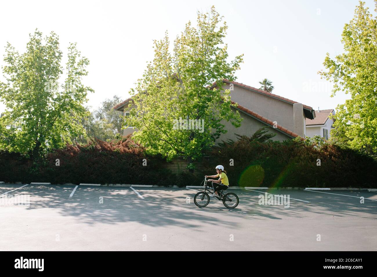 Profil de tir large de la jeune fille à vélo dans un parking Banque D'Images