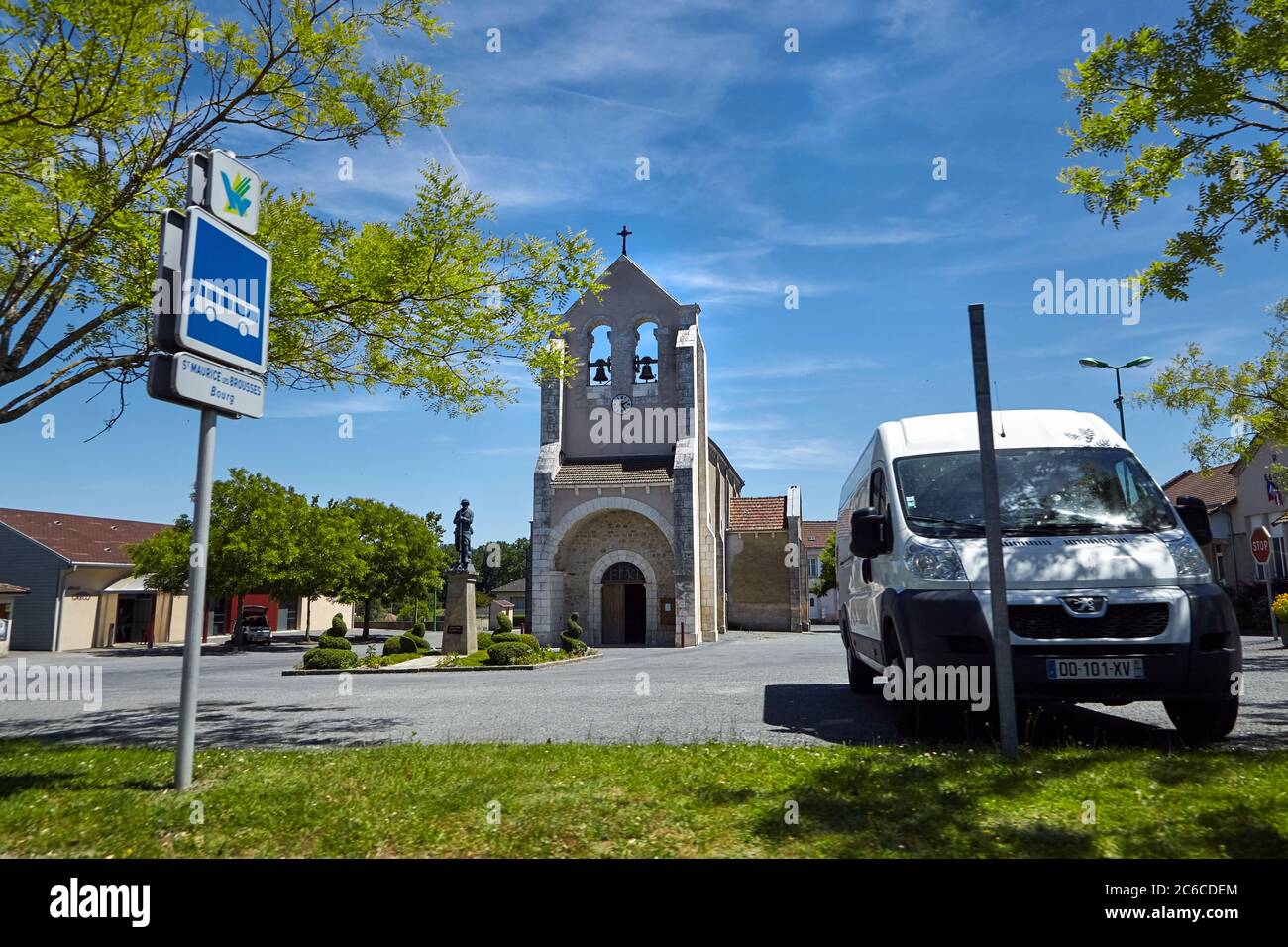Saint-Maurice-les-Brousses, haute-Vienne, France - 23 juin 2018 : place de l'Église. Сhurch avec des cloches et le mémorial de guerre. Fourgonnette garée à l'ombre o Banque D'Images
