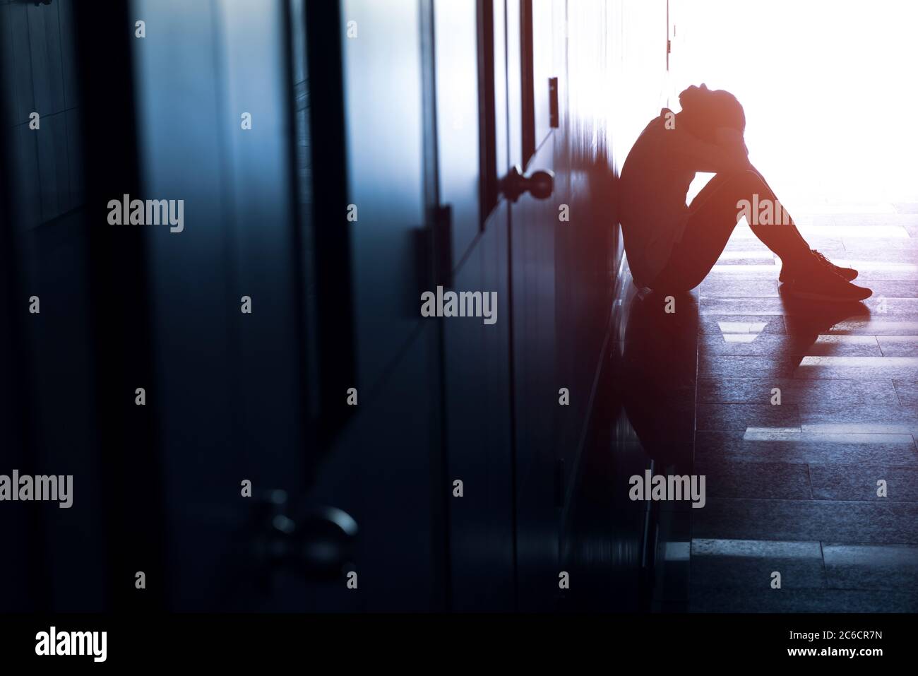 Silhouette d'homme déprimé assis sur la passerelle du bâtiment. Triste homme, Cry, drame, solitaire et malheureux concept. Banque D'Images
