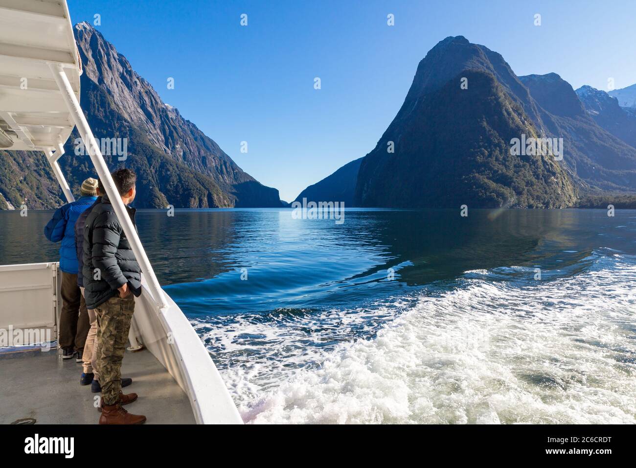 Les touristes mâles à bord d'un bateau de croisière dans le Milford Sound regardent vers Mitre Peak, parc national Fiordland, Nouvelle-Zélande Banque D'Images