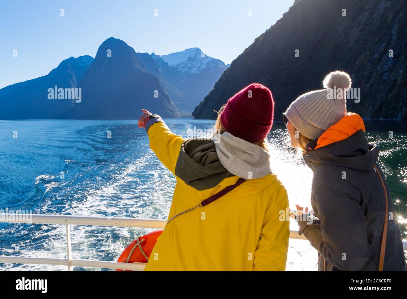 Les touristes féminins à bord d'un bateau de croisière dans le Milford Sound pointent vers le pic de Mitre, parc national de Fiordland, Nouvelle-Zélande Banque D'Images