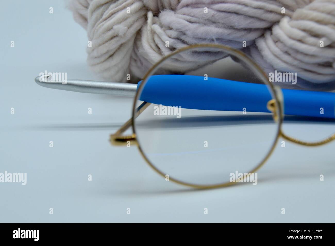 Paire de lunettes de lecture granny dans un studio à fond blanc tourné en gros plan avec boule de flocons d'avoine biologique de laine et un crochet en métal et en plastique crochet Banque D'Images