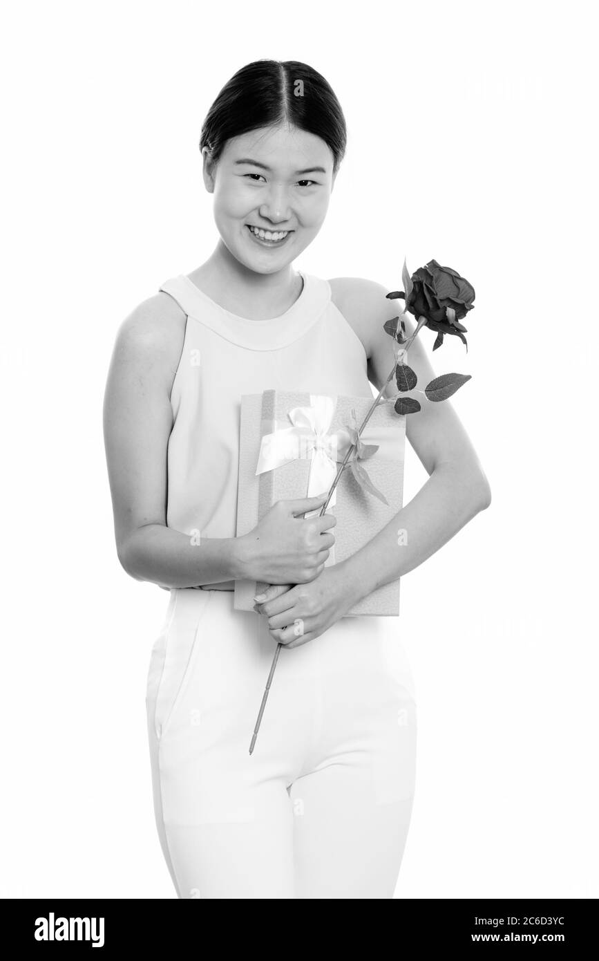 Jeune femme asiatique heureuse souriant tout en tenant la rose rouge et boîte cadeau prêt pour la Saint-Valentin Banque D'Images