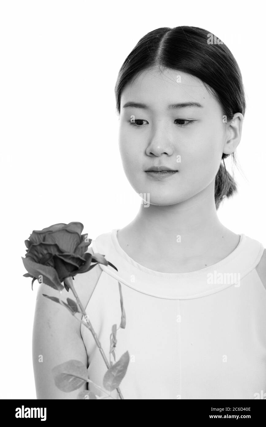 Gros plan de la jeune femme asiatique belle tenant et regardant la rose rouge Banque D'Images