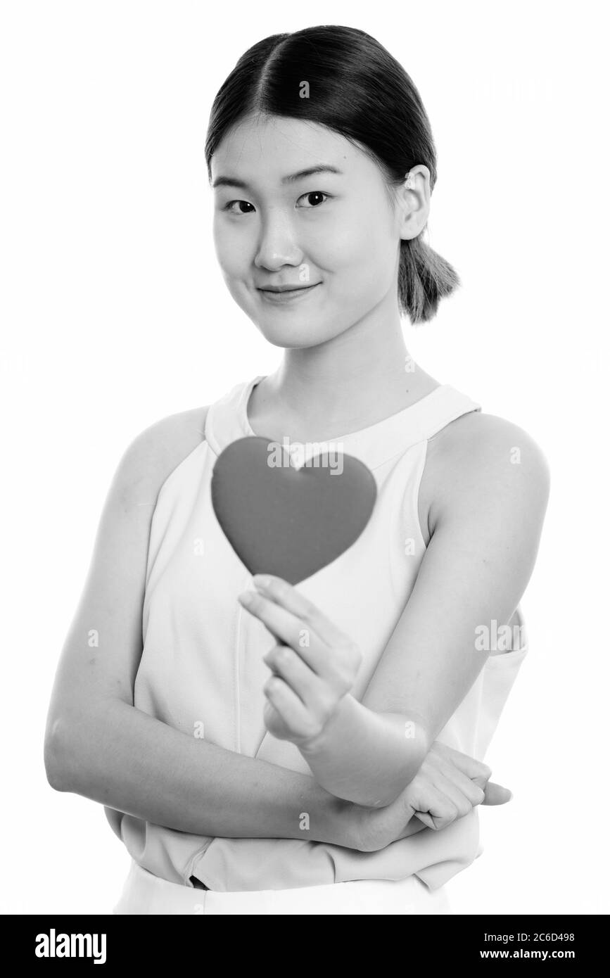 Studio shot of young beautiful Asian woman holding red heart Banque D'Images