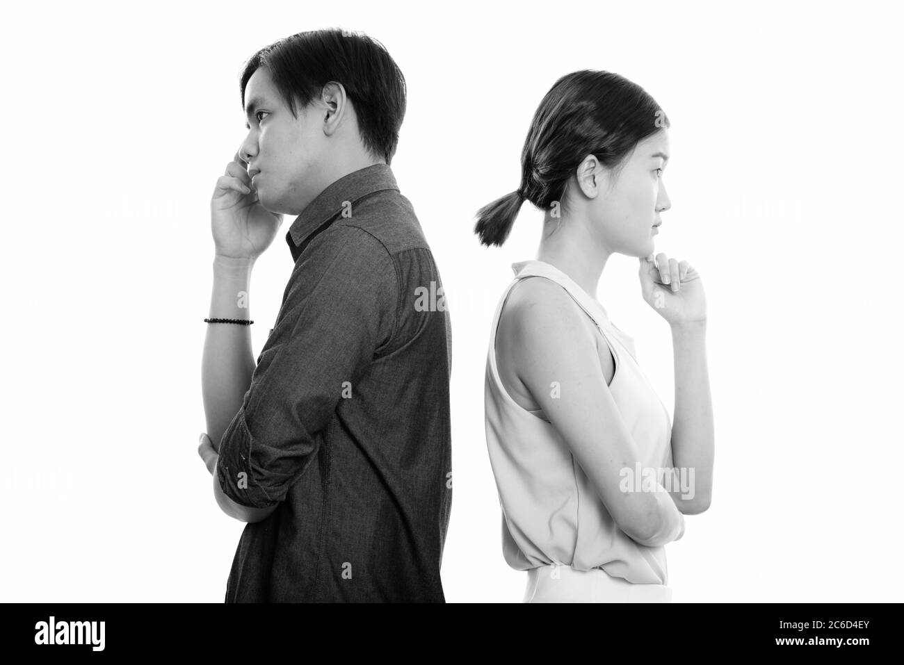 Vue de profil des jeunes couples asiatiques qui pensent ensemble avec des dos contre les uns les autres Banque D'Images