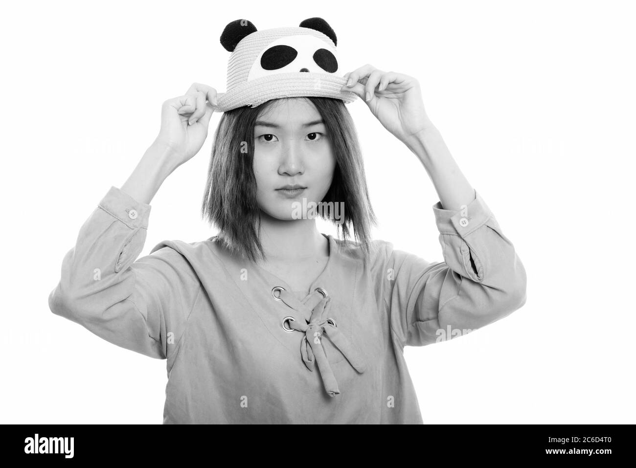 Photo studio d'une jeune femme asiatique magnifique tenant un chapeau des deux mains Banque D'Images