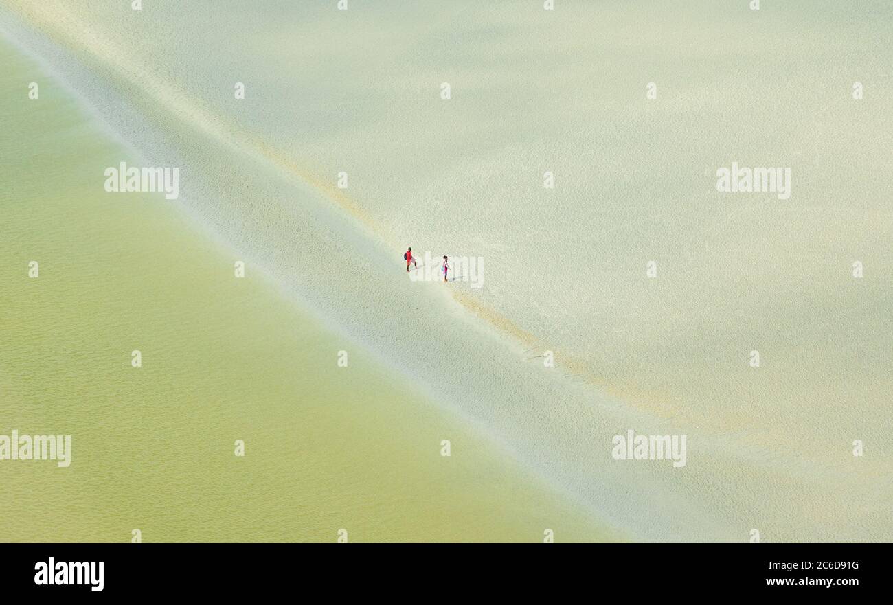 Paysage avec l'embouchure de la rivière vue du Mont Saint Michel et couple méconnaissable marchant à marée basse fond de l'océan loin. Liberté, peu de pers Banque D'Images
