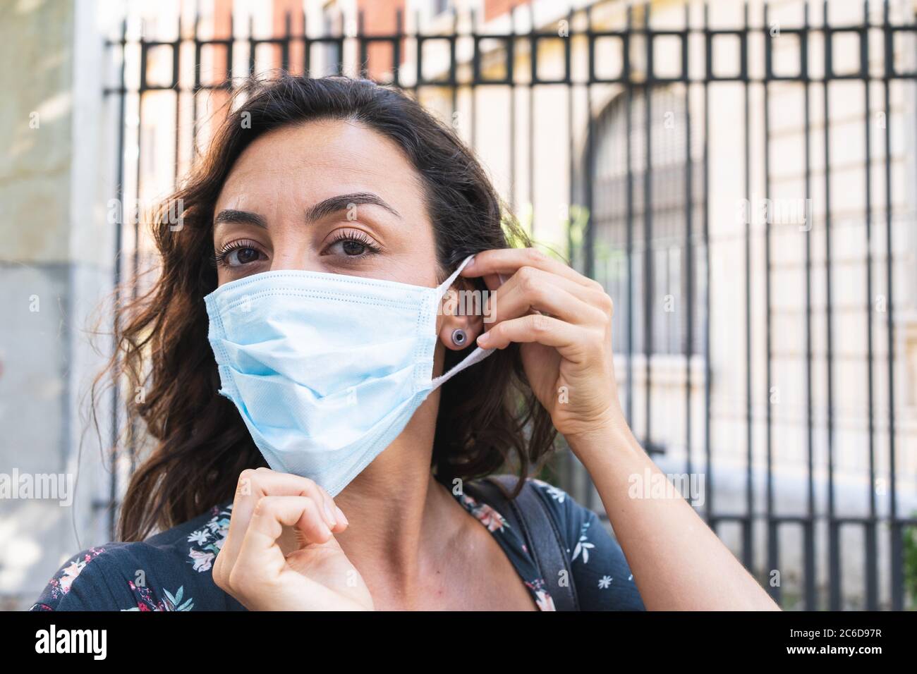 Jeune femme mettant un masque chirurgical dans la rue pour se protéger et prendre des mesures de sécurité hygiéniques. Concept de protection et de sécurité Banque D'Images