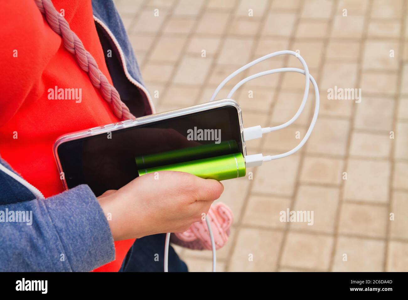 Elle tient un smartphone et une batterie externe pendant la charge Banque D'Images
