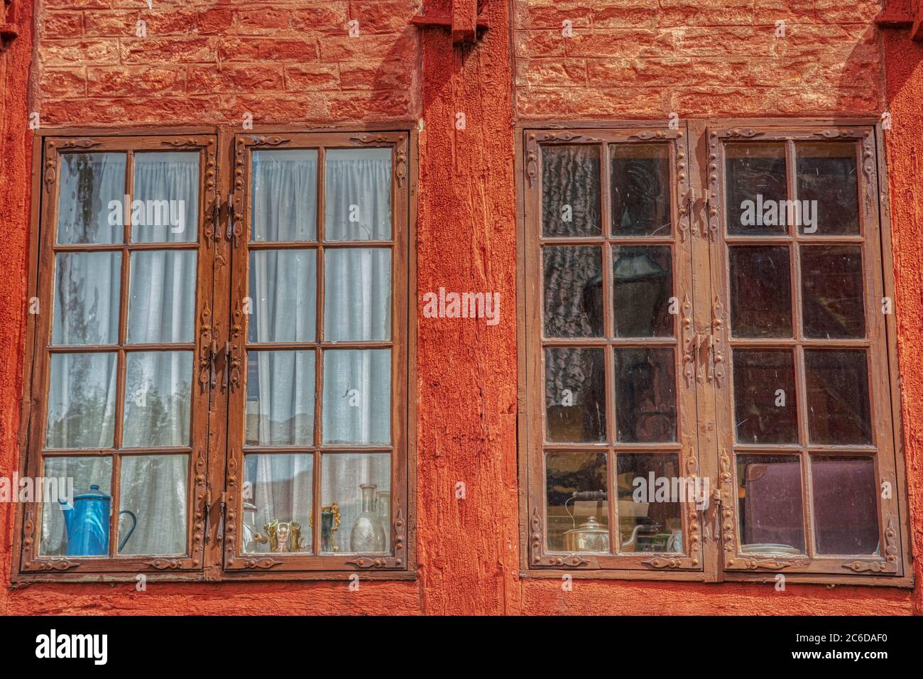 Deux anciennes fenêtres en bois sur une façade en bois des années 60. Une théière est à la fenêtre et un intérieur traditionnel de l'après-guerre apparaît à travers le petit verre Banque D'Images