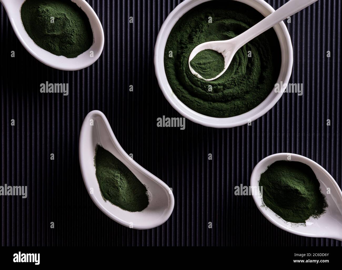 Poudre de chlorelle ou de spiruline vert naturel dans quatre bols en porcelaine blanche de forme différente. Concept de nourriture saine et de régime. Design bl Banque D'Images