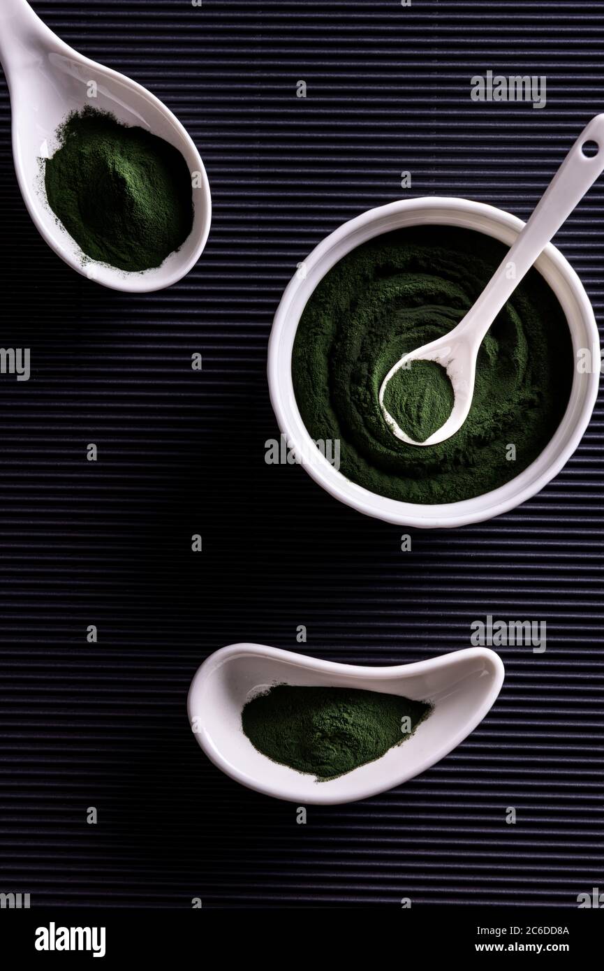 Poudre de chlorelle ou de spiruline vert naturel dans trois bols en porcelaine blanche de forme différente. Concept de nourriture saine et de régime. Élégant b Banque D'Images