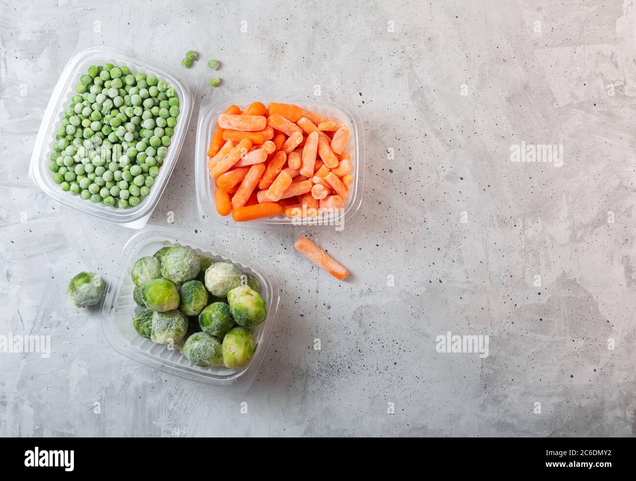 Legumes Surgeles Tels Que Les Pois Verts Les Choux De Bruxelles Et La Carotte De Bebe Dans Les Boites De Rangement Sur Fond Gris En Beton Vue Du Dessus Avec Espace Pour
