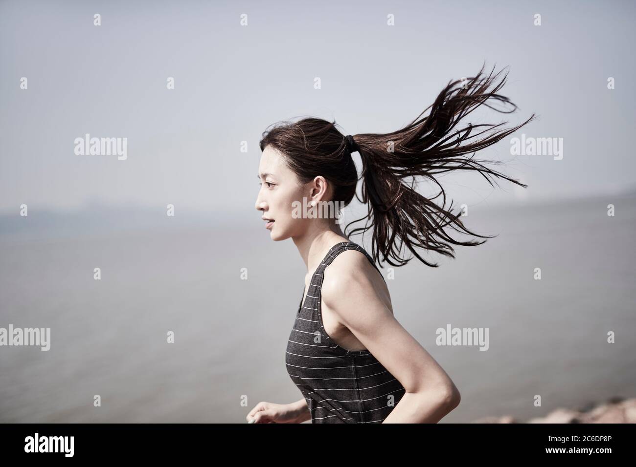 jeune femme adulte asiatique courant à l'extérieur au bord de la mer Banque D'Images