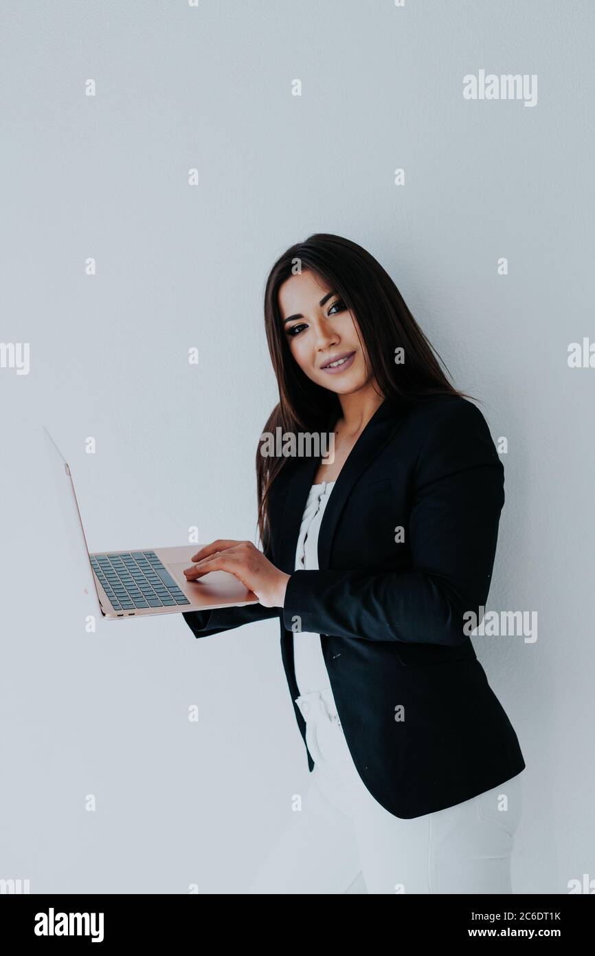 Belle femme brune en blanc et noir vêtements d'affaires dans le bureau avec un ordinateur portable Banque D'Images