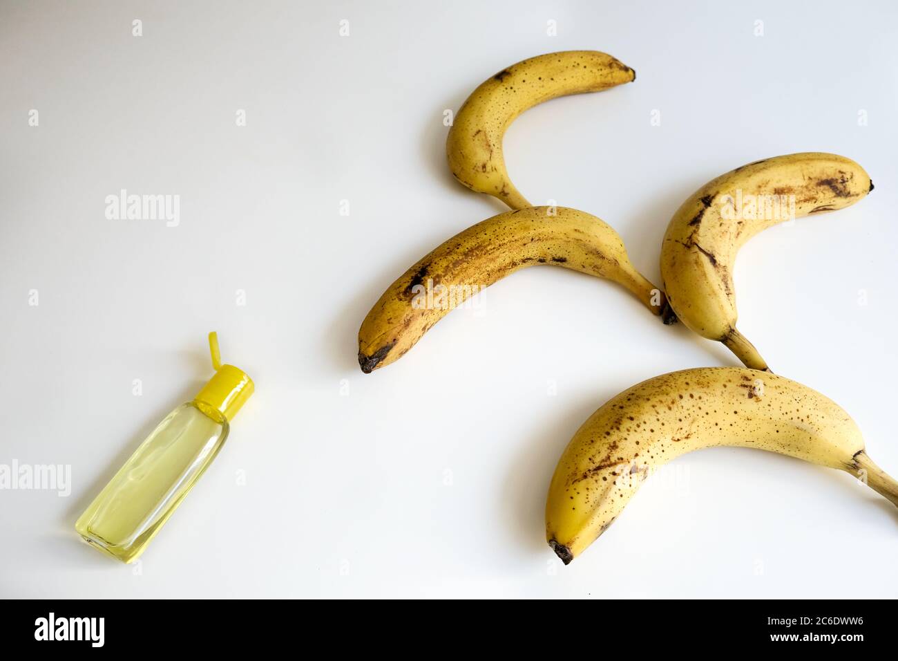 Concept créatif pour l'épidémie de coronavirus. Bouquet de bananes mûres à pois et bouteille ouverte de désinfectant jaune pour les mains. Table blanche avec espace vide Banque D'Images