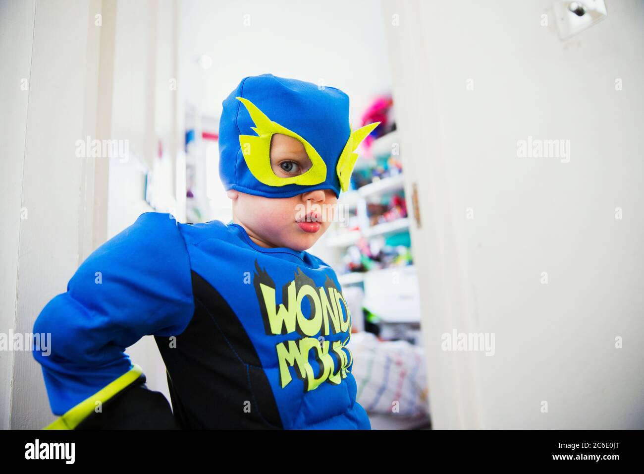 Garçon en costume de super-héros posant à la porte de sa chambre Banque D'Images