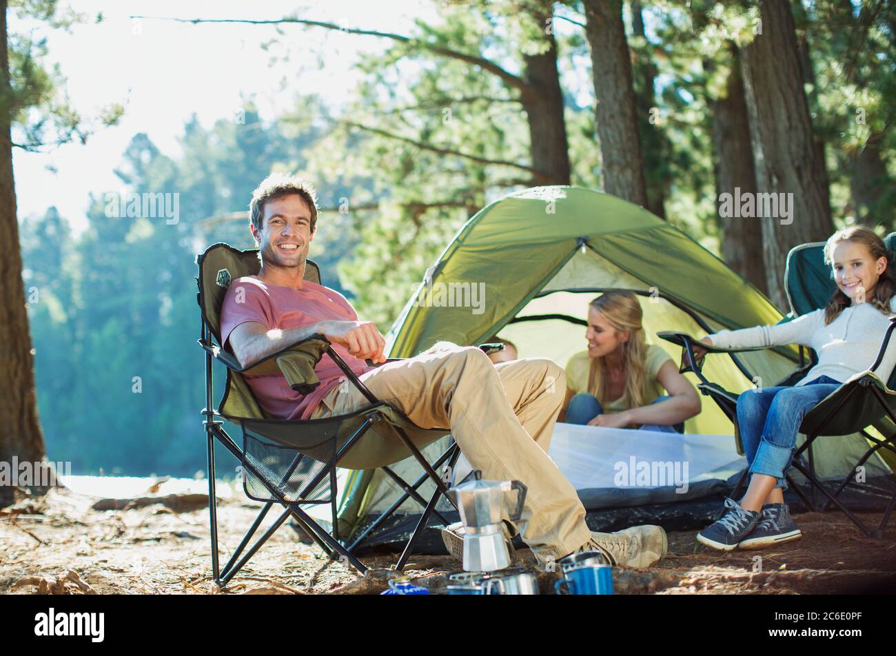 Famille souriante se détendre au camping dans les bois Banque D'Images