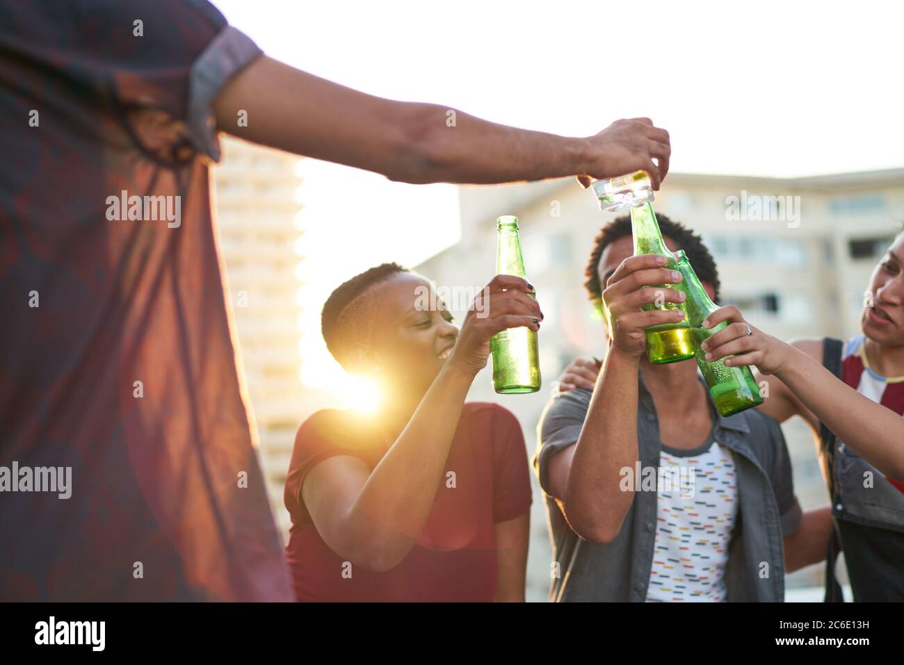 De jeunes amis toaster des verres à bière sur le toit urbain ensoleillé Banque D'Images