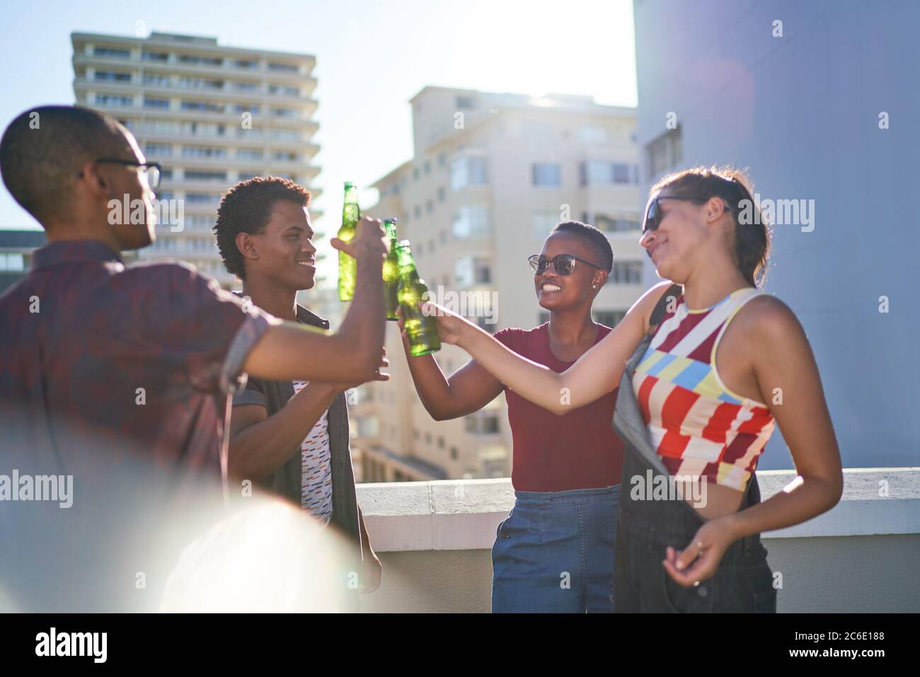 De jeunes amis heureux buvant de la bière sur le toit urbain ensoleillé Banque D'Images