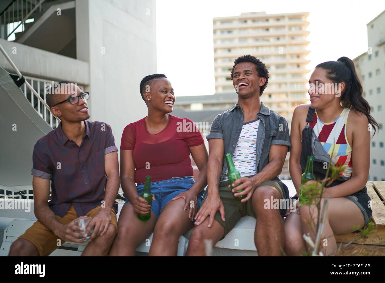 De jeunes amis heureux buvant de la bière sur le toit urbain Banque D'Images