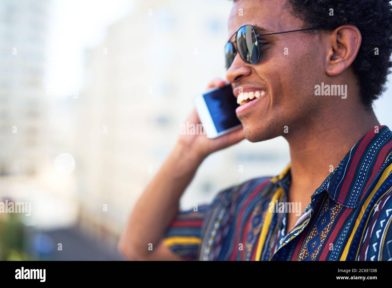 Jeune homme souriant parlant sur un smartphone Banque D'Images