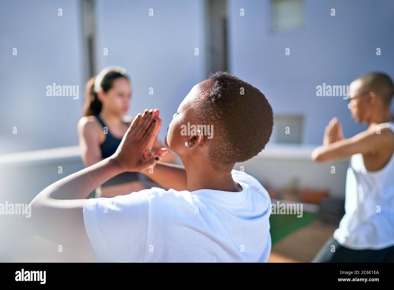 Sereine jeune femme pratiquant le yoga sur un balcon ensoleillé Banque D'Images Sereine jeune femme pratiquant le yoga sur un balcon ensoleillé Banque D'Images