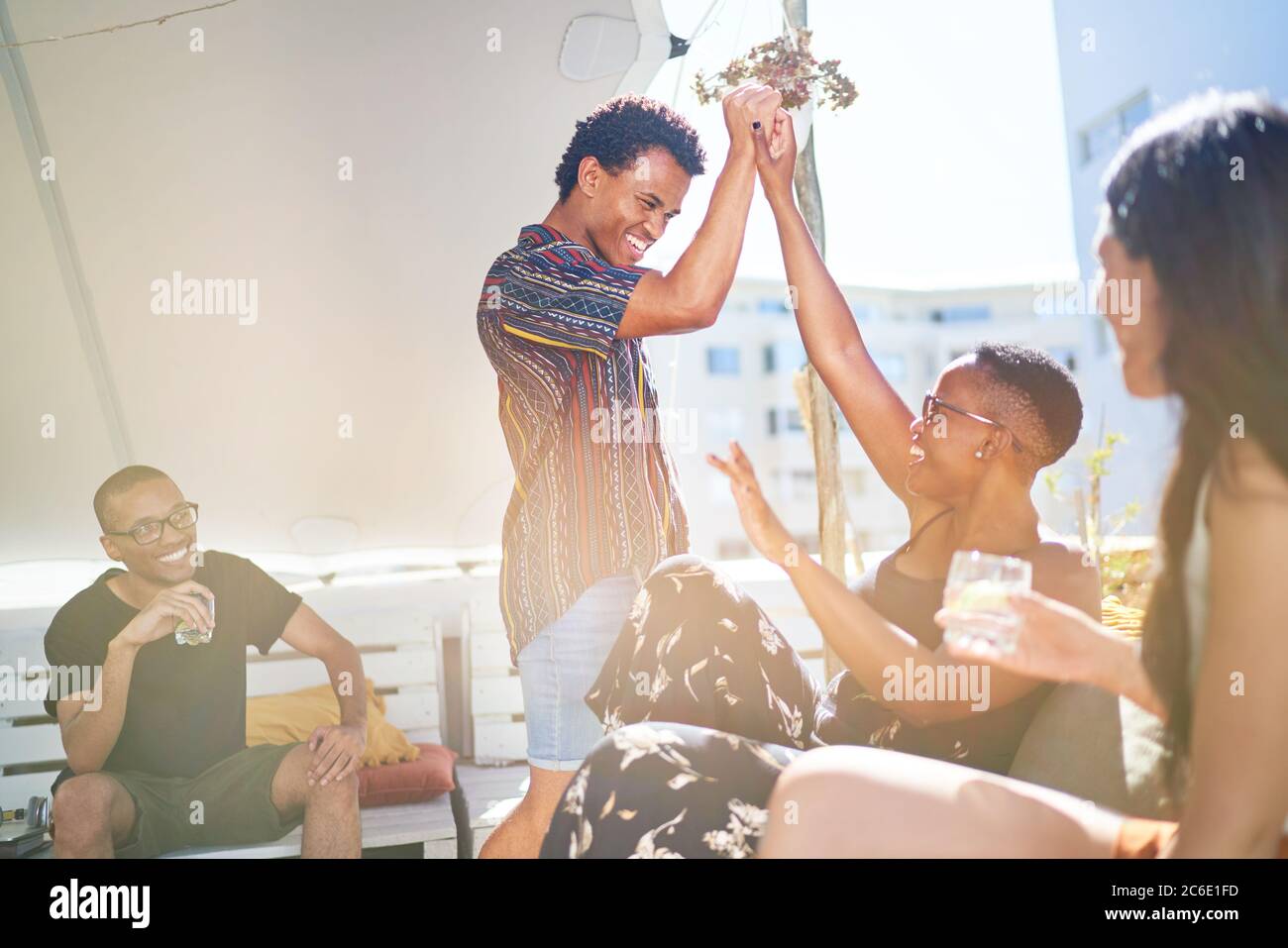 De jeunes amis heureux se sont élevés sur le balcon ensoleillé sur le toit Banque D'Images