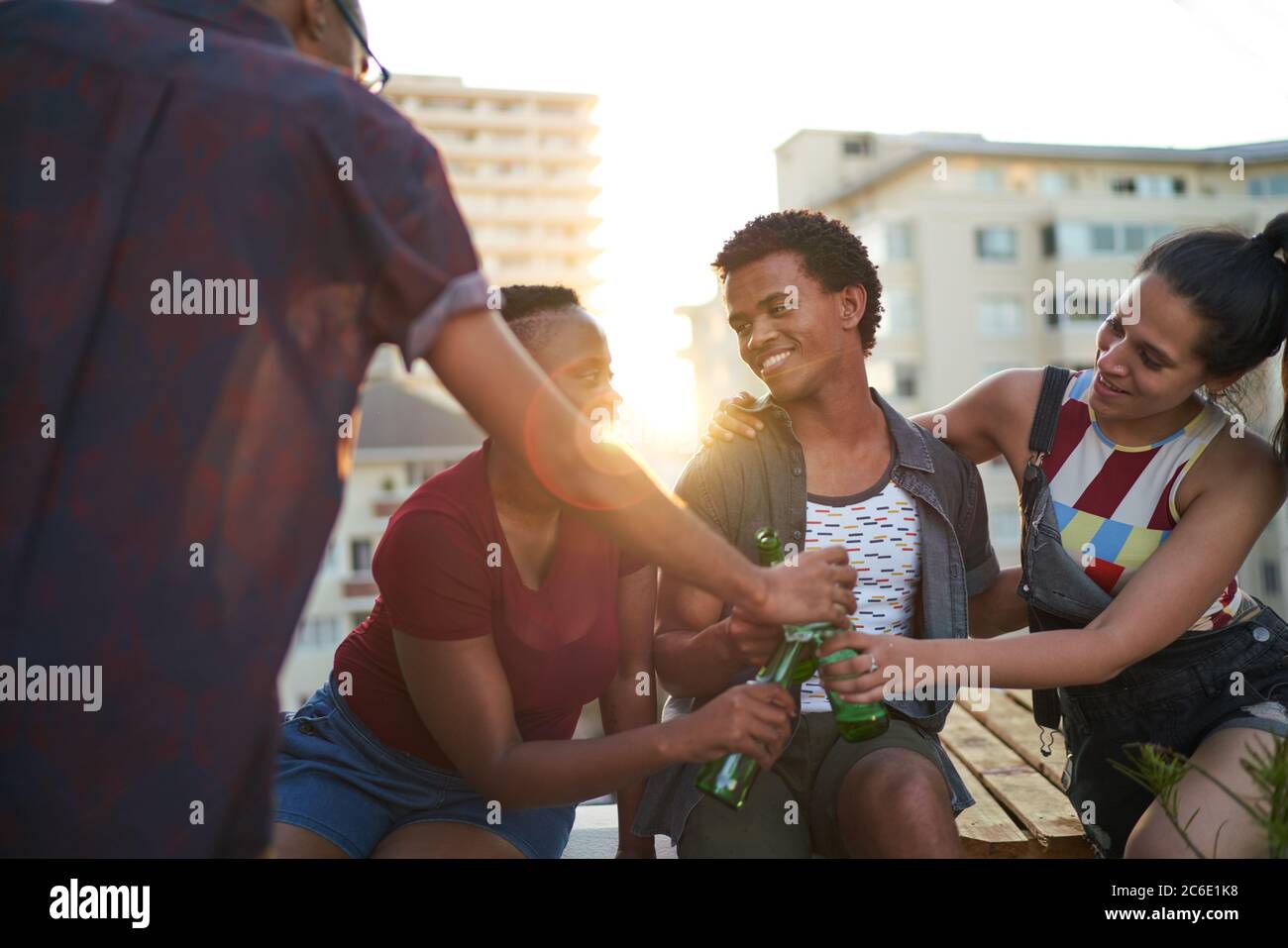 De jeunes amis heureux buvant de la bière sur le balcon urbain ensoleillé sur le toit Banque D'Images