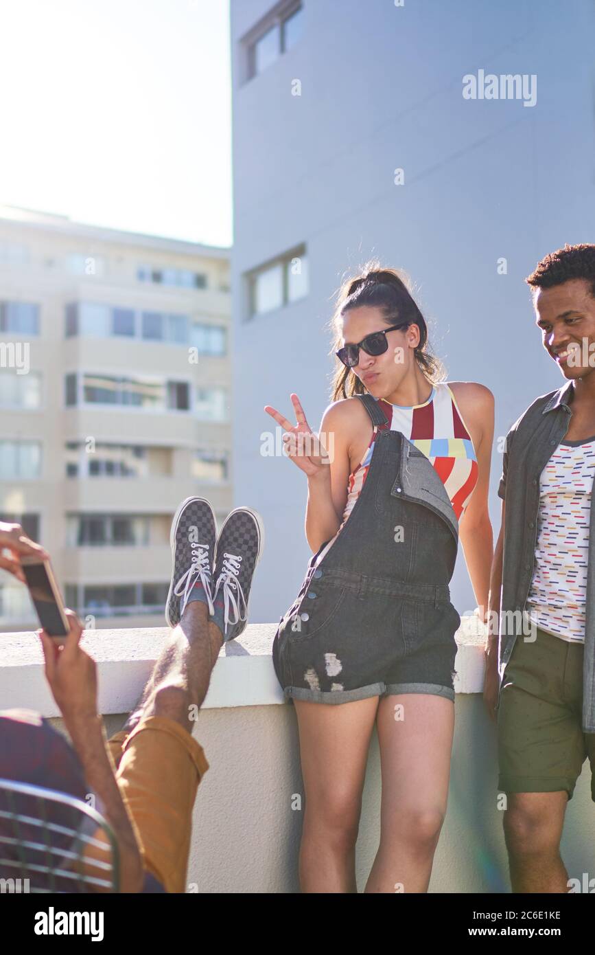 Jeune femme sympa signe de paix sur le toit urbain ensoleillé Banque D'Images