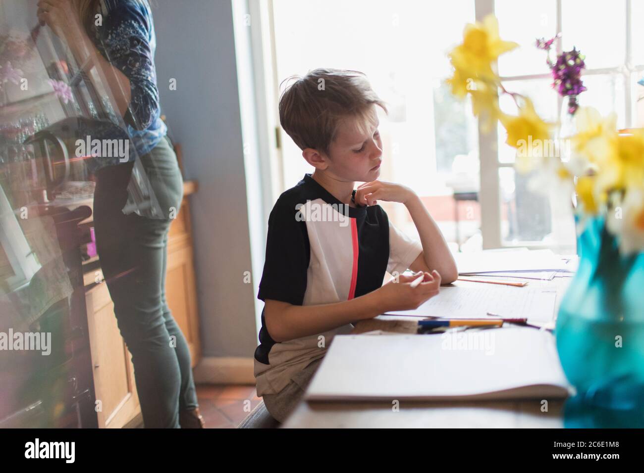Boy doing homework at kitchen table Banque D'Images