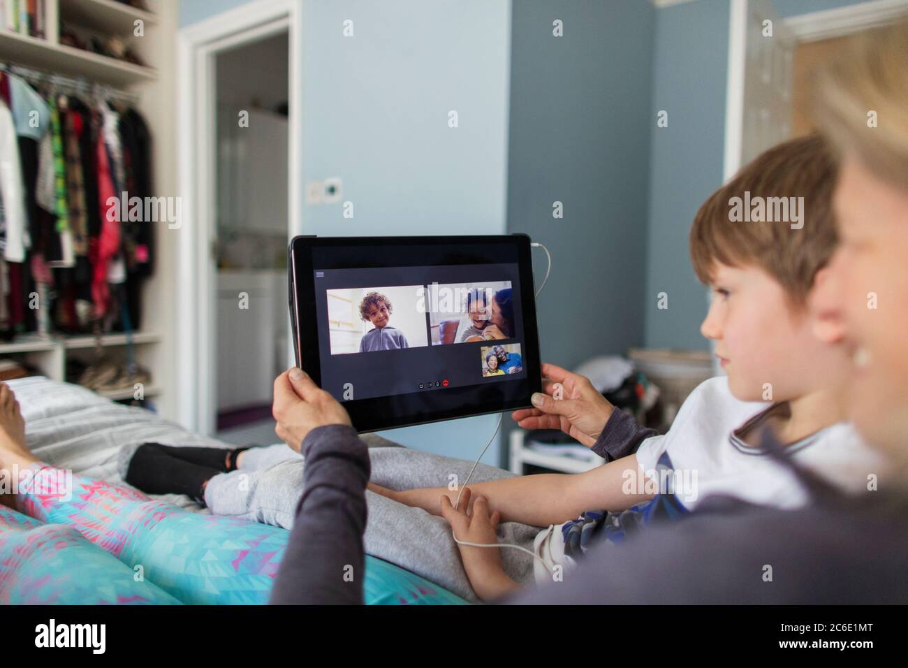 Chat vidéo familial avec une tablette numérique sur le lit Banque D'Images