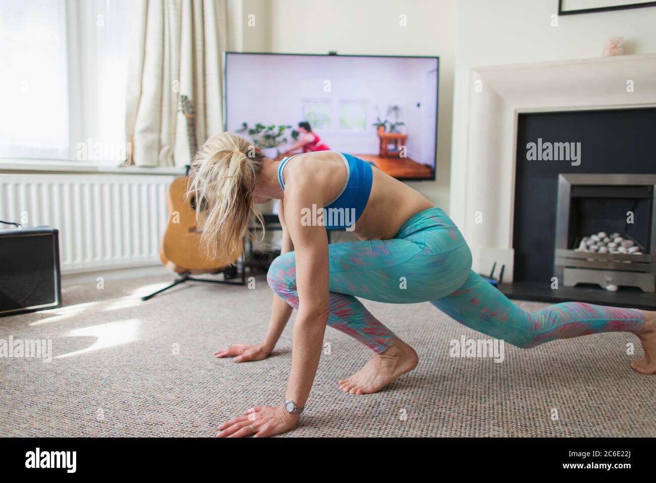 Femme pratiquant le yoga en ligne dans le salon Banque D'Images