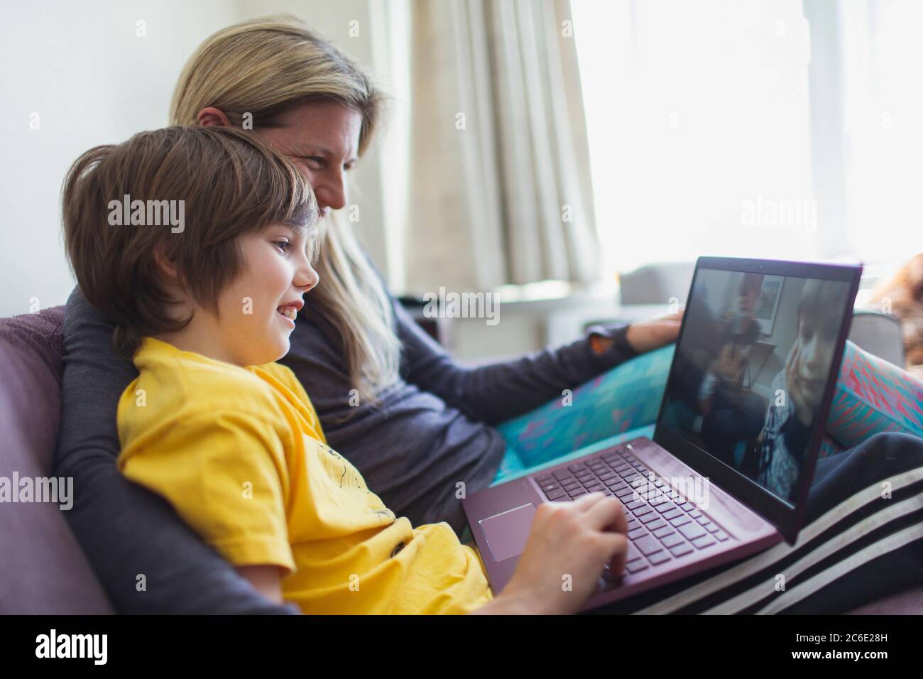 Mère et fils utilisant un ordinateur portable sur le canapé Banque D'Images