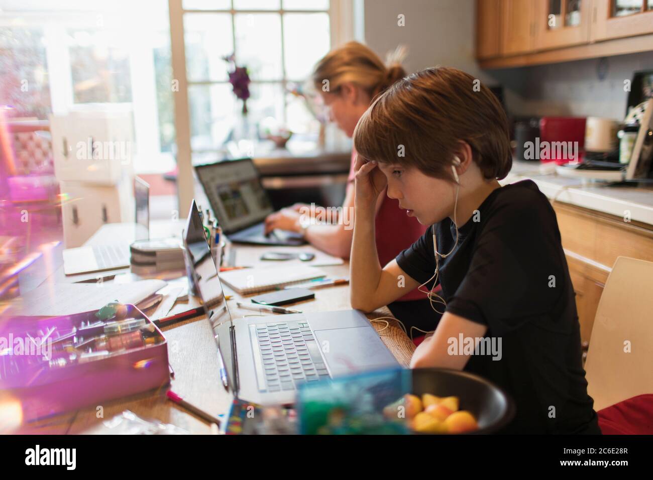 Un garçon qui se concentre sur l'ordinateur portable dans la cuisine Banque D'Images