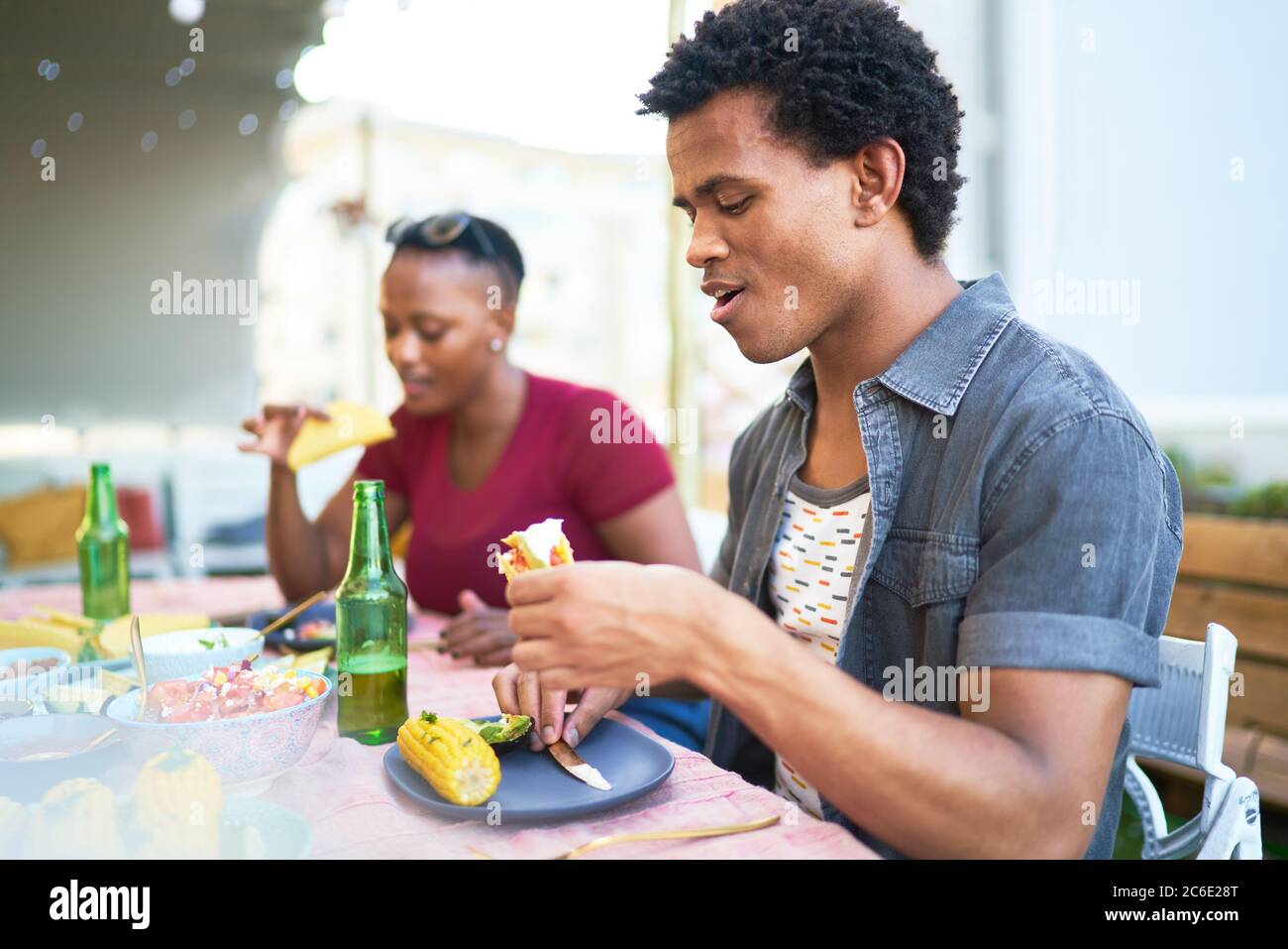 Un jeune homme mange un déjeuner à tacos à la table du patio Banque D'Images