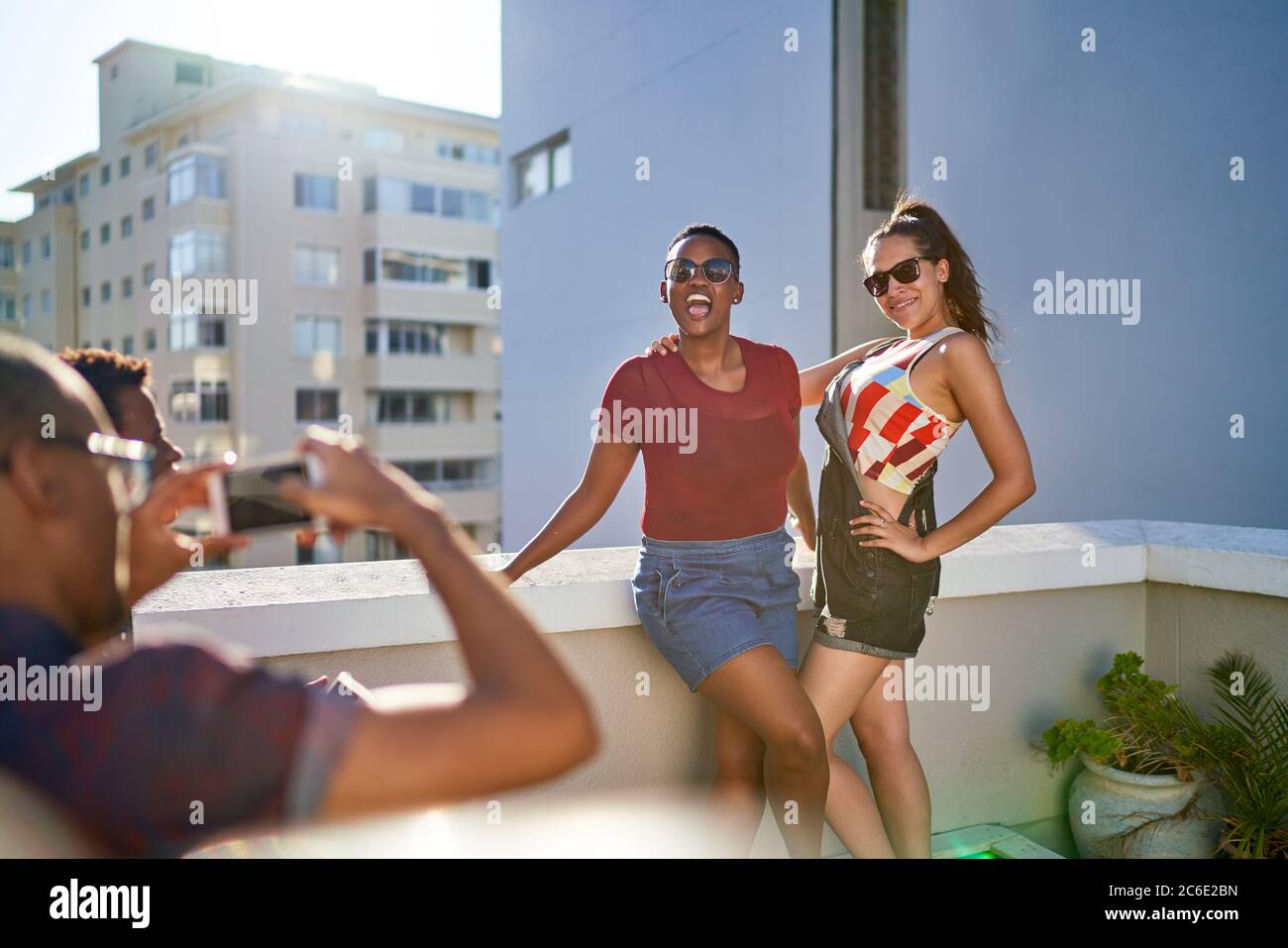 De jeunes amies joyeuses posant pour la photo sur un balcon urbain ensoleillé Banque D'Images