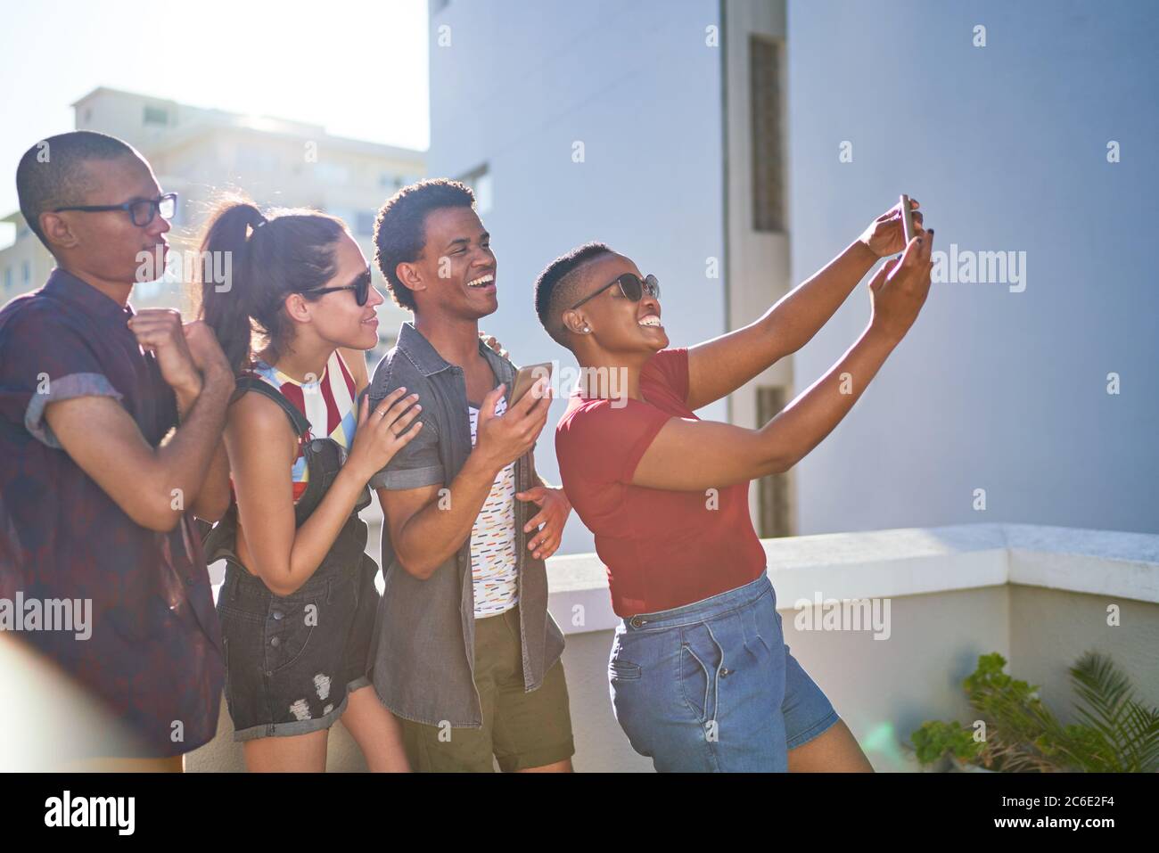 De jeunes amis heureux prenant le selfie sur le balcon urbain ensoleillé Banque D'Images