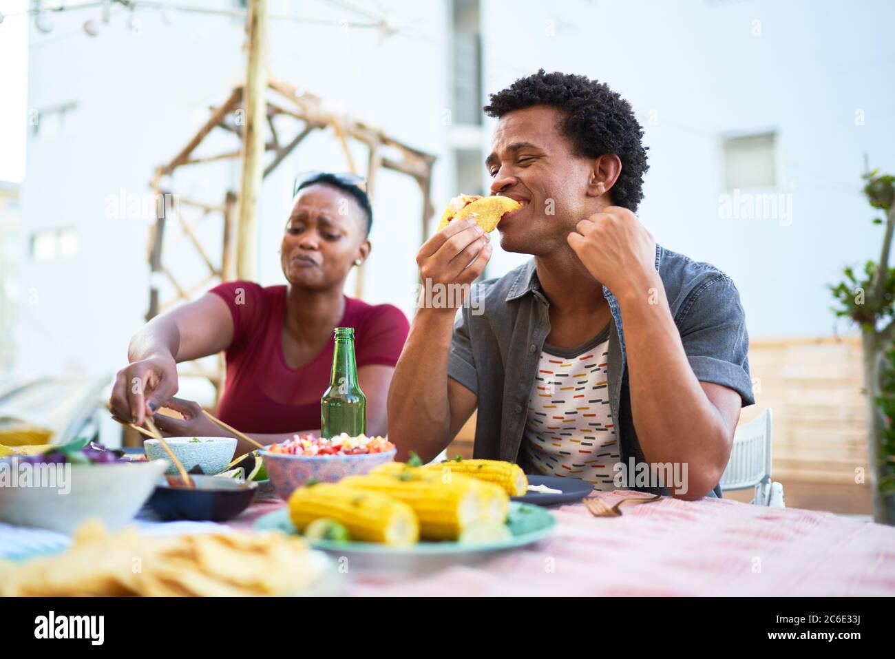 Un jeune homme mange un déjeuner à tacos à la table du patio Banque D'Images