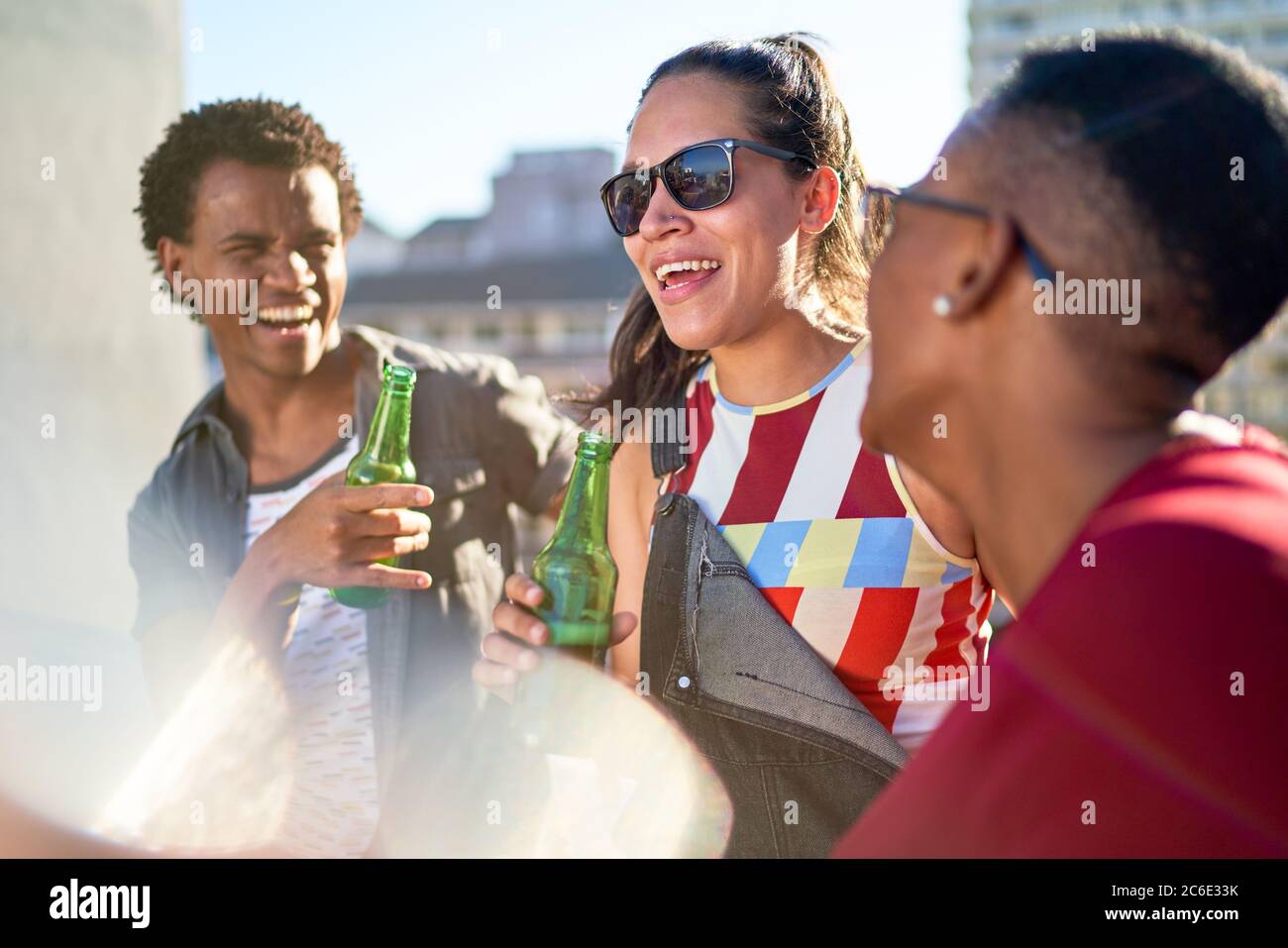 De jeunes amis heureux buvant de la bière sur un balcon ensoleillé Banque D'Images