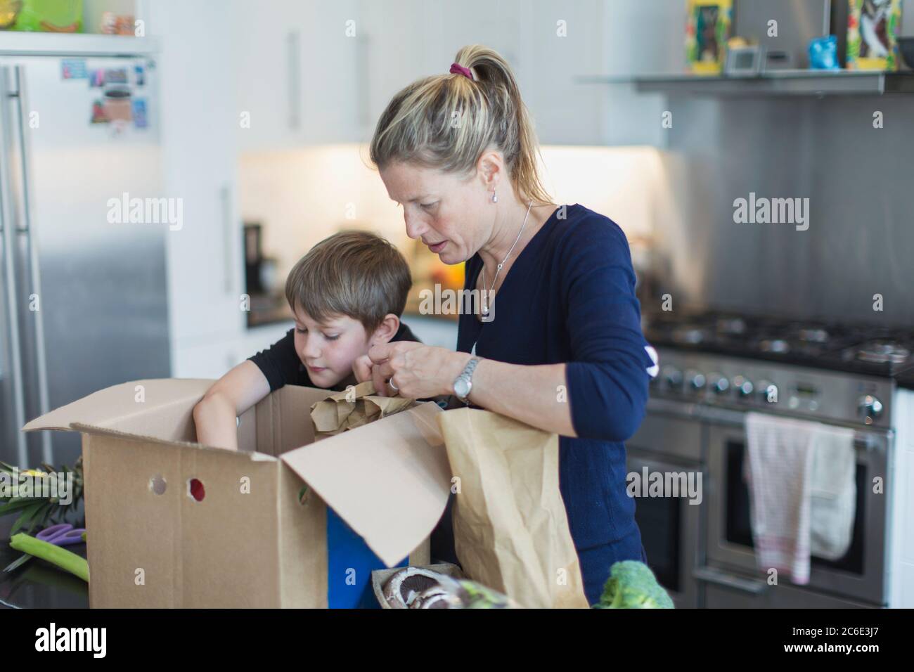 Mère et fils déchargeant les produits de la boîte dans la cuisine Banque D'Images