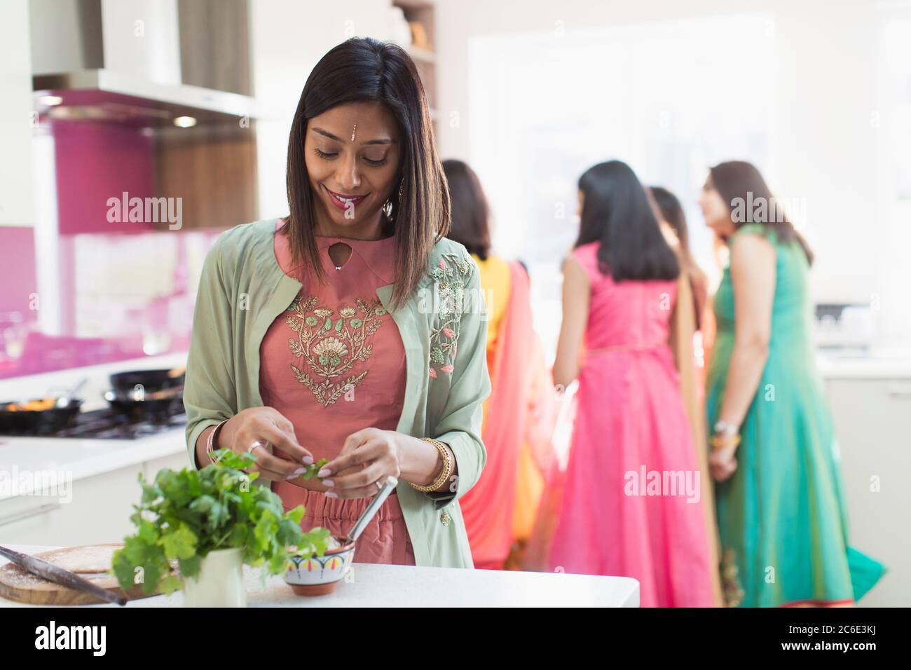 Femme indienne à sari et lier la cuisine avec la famille dans la cuisine Banque D'Images