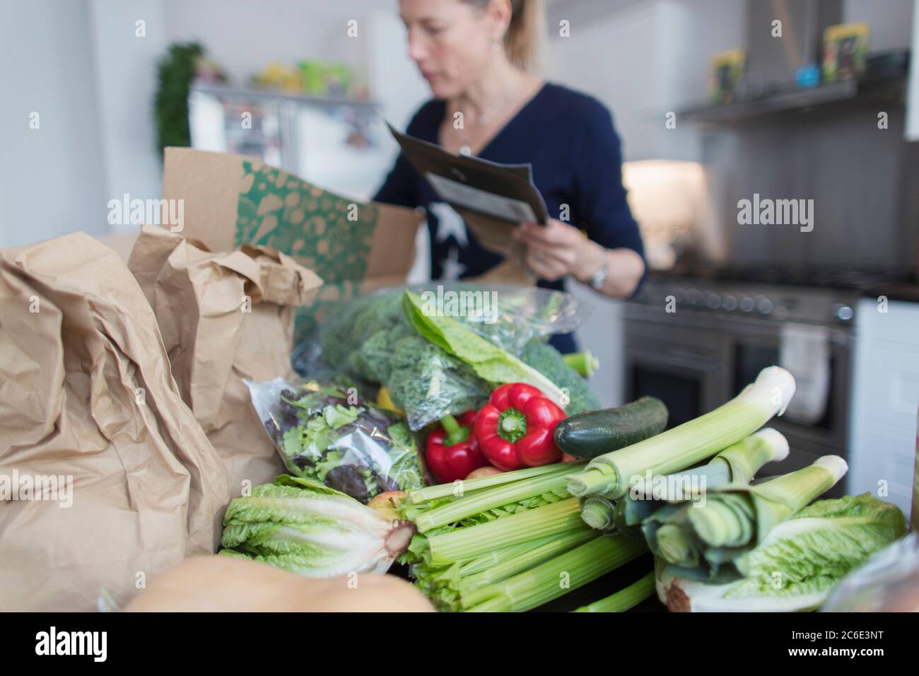 Femme déchargeant des produits frais de la boîte dans la cuisine Banque D'Images