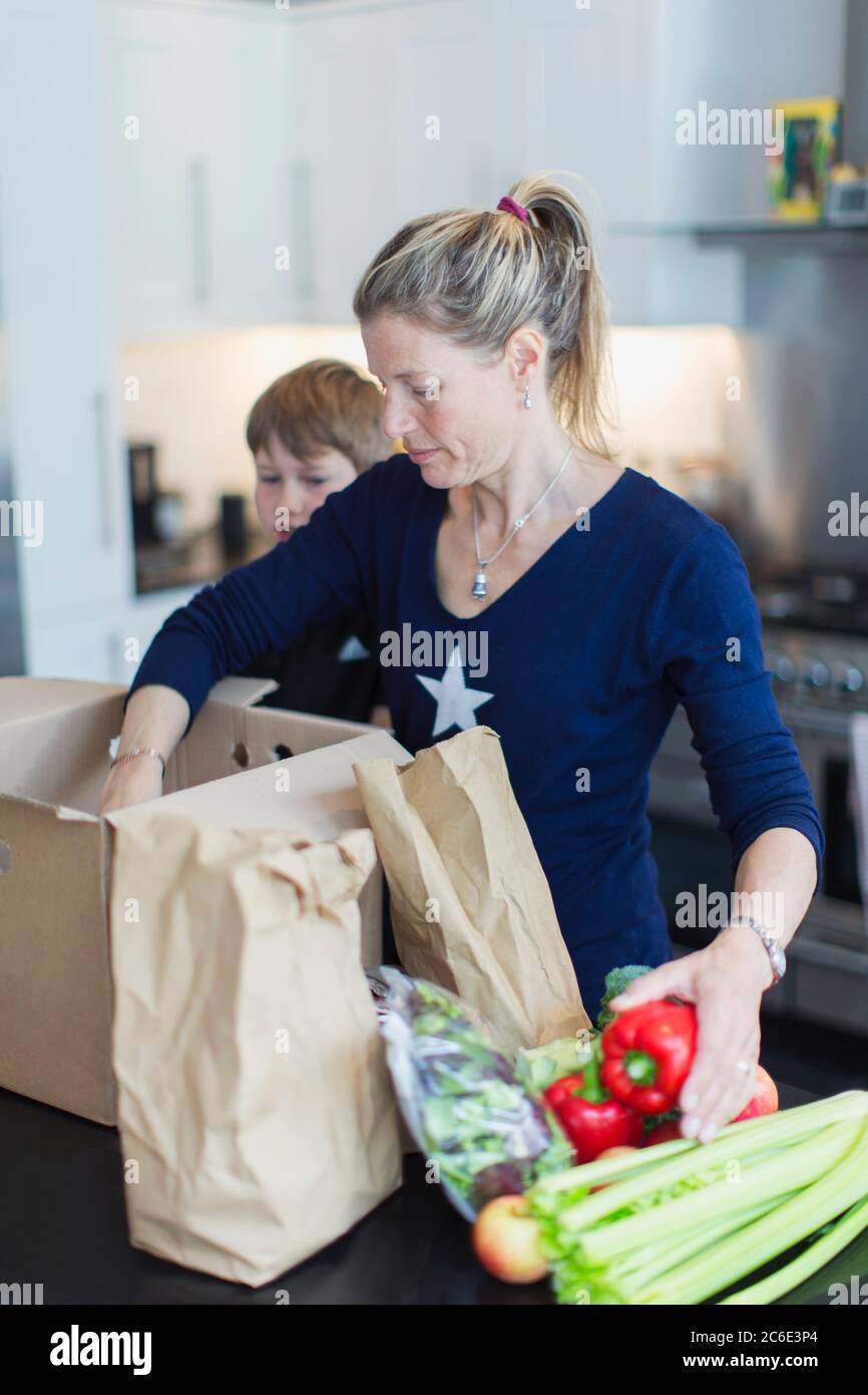 Mère et fils déchargeant des produits frais dans la cuisine Banque D'Images