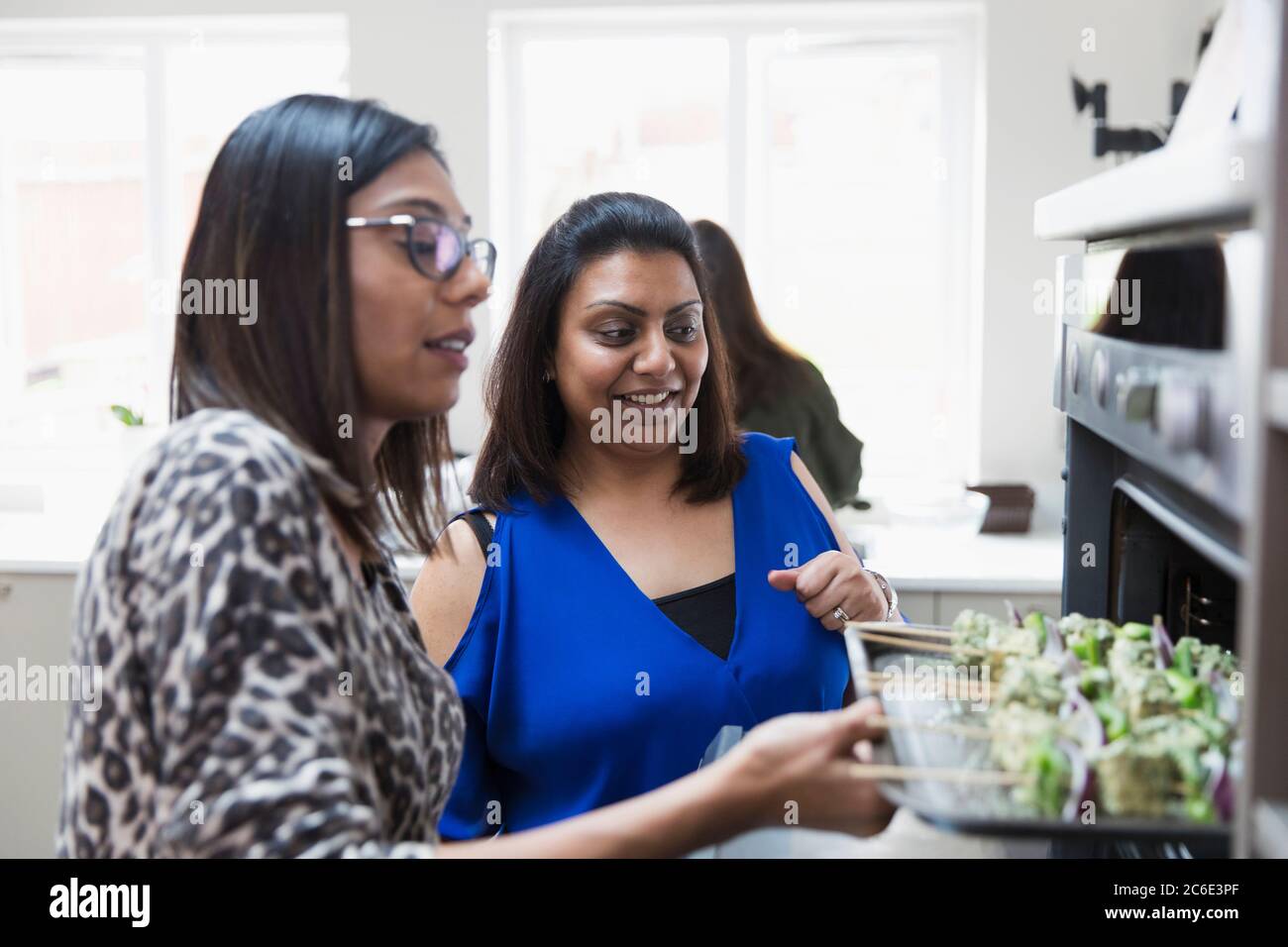 Femmes indiennes plaçant kebabs dans le four dans la cuisine Banque D'Images