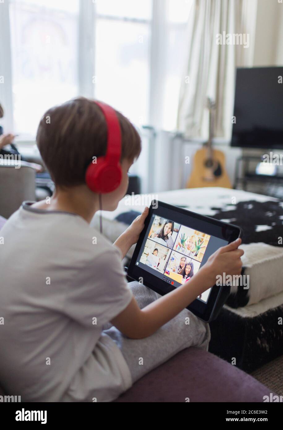 Garçon avec casque et tablette numérique homeschooling sur le canapé Banque D'Images